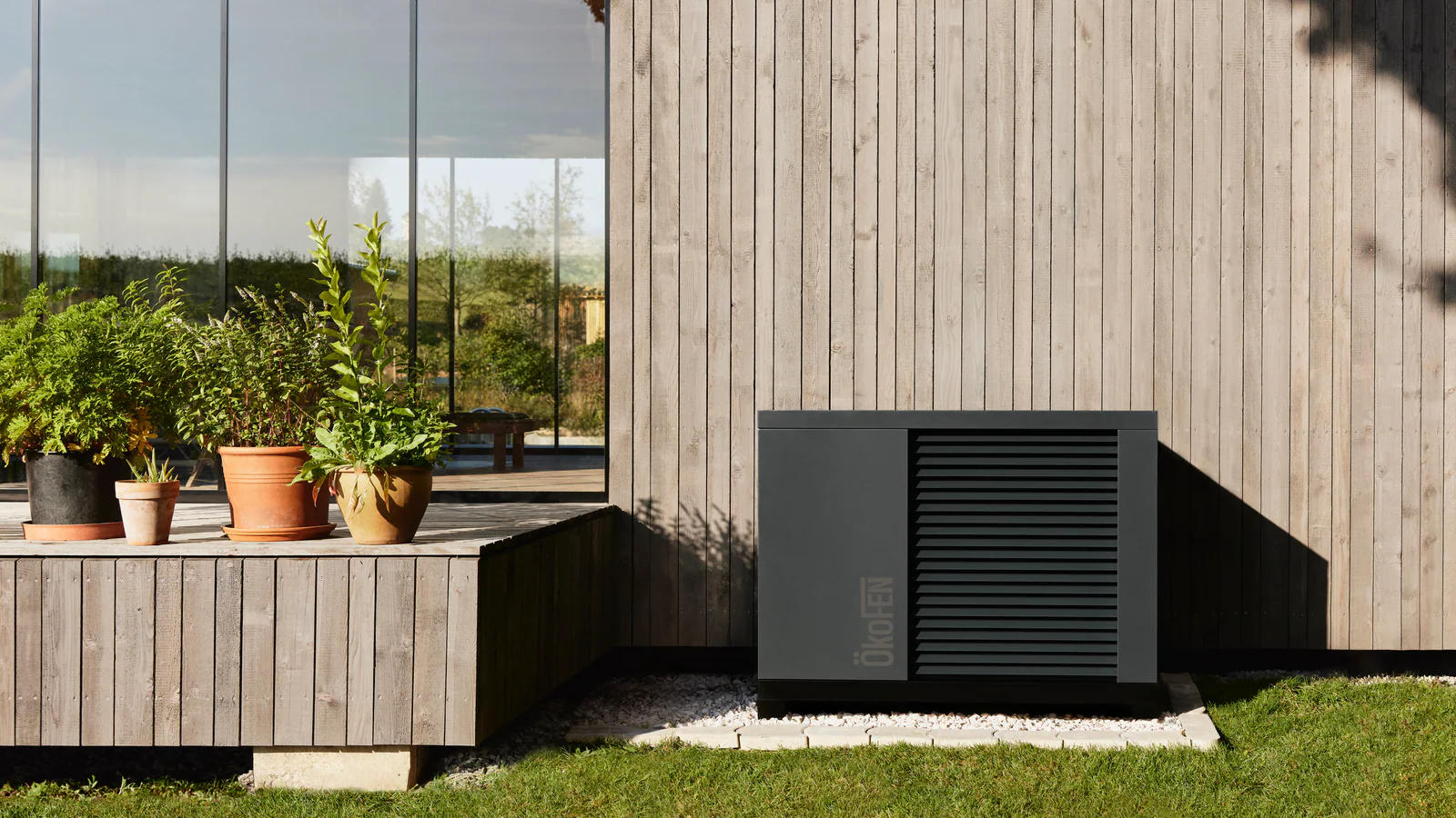Wärmepumpe an einem Wohnhaus mit Holzfassade